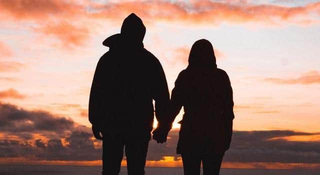 Couple holding hands in front of a sunset